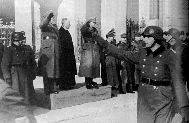 Slavnostni mimohod domobranskih čet pred Uršulinsko cerkvijo v Ljubljani, 30. januarja 1945. Na piedestalu stojijo: Leon Rupnik, poveljnik domobranskih enot, škof Gregorij Rožman in Erwin Rösener, poveljnik nemških čet.