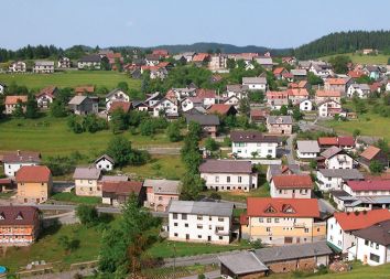 Z iste točke posneta fotografija desno od idiličnega pogleda na staro vas razkriva pogled na pozidano pobočje z značilno kaotično pozidavo slovenskega podeželja.