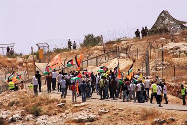 Skupina palestinskih, izraelskih in mednarodnih demonstrantov pred ograjo, s katero je bila palestinski vasi Bil''in odvzeta več kot polovica zemlje.