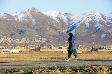 Deklica na skejtu, v ozadju predmestje Kabula. Polovica otrok, ki se učijo skejtanja v okviru projekta Skateistan, je ženskega spola. Afganistan ima tako največji delež ženskih skejterjev na svetu.